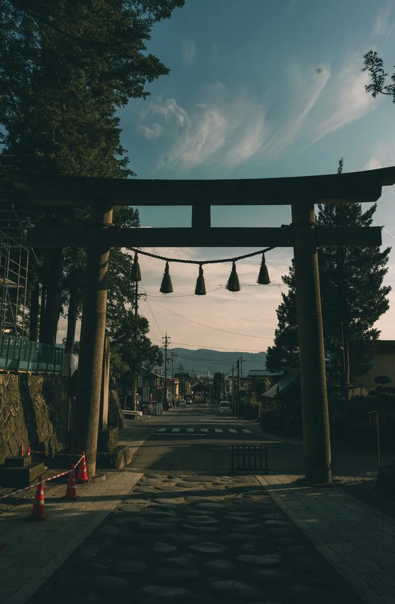 A shrine gate framed by trees above a stone path.